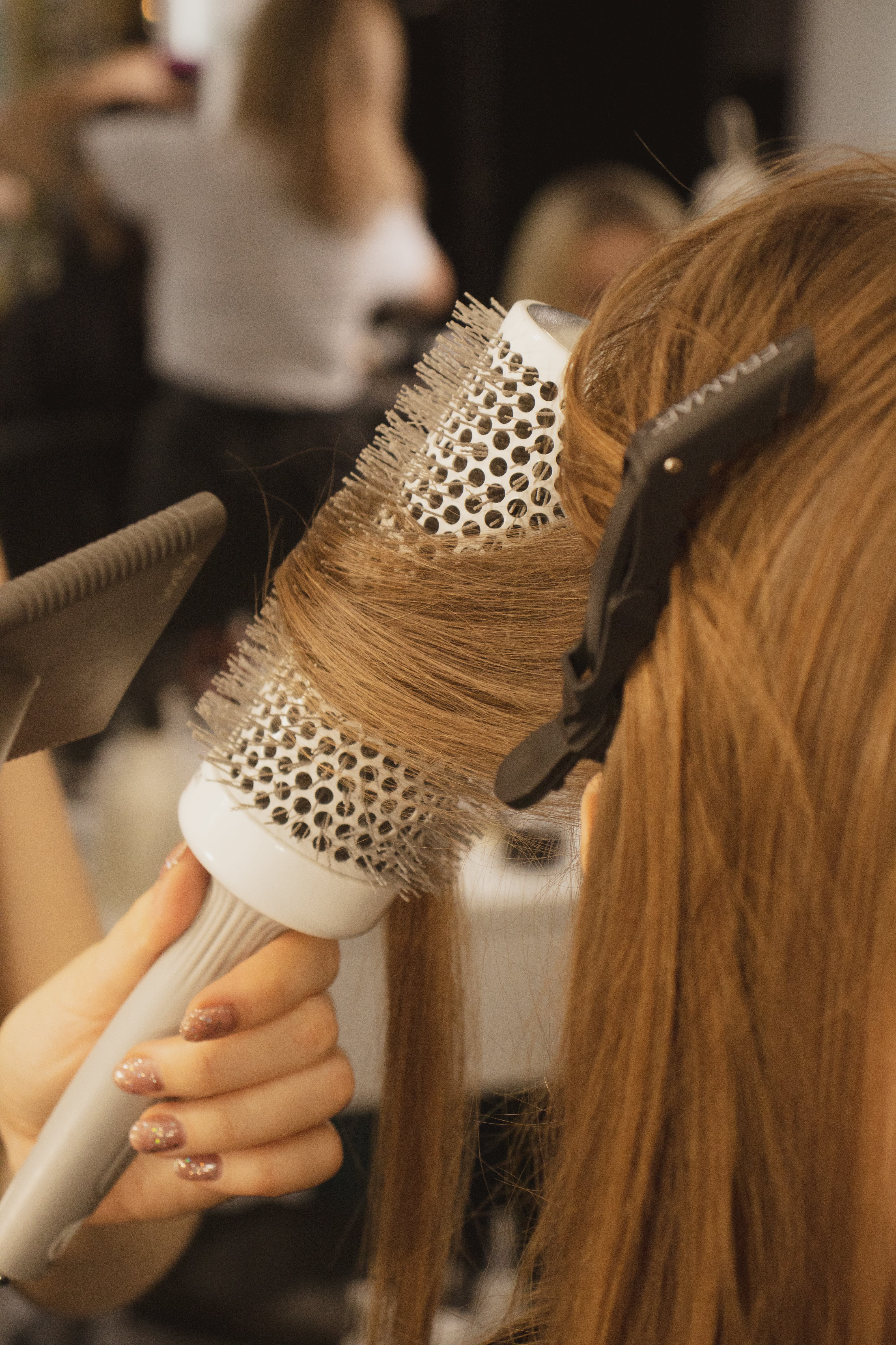 une hairstylist faisant un brushing sur un modèle dans un salon de coiffure
